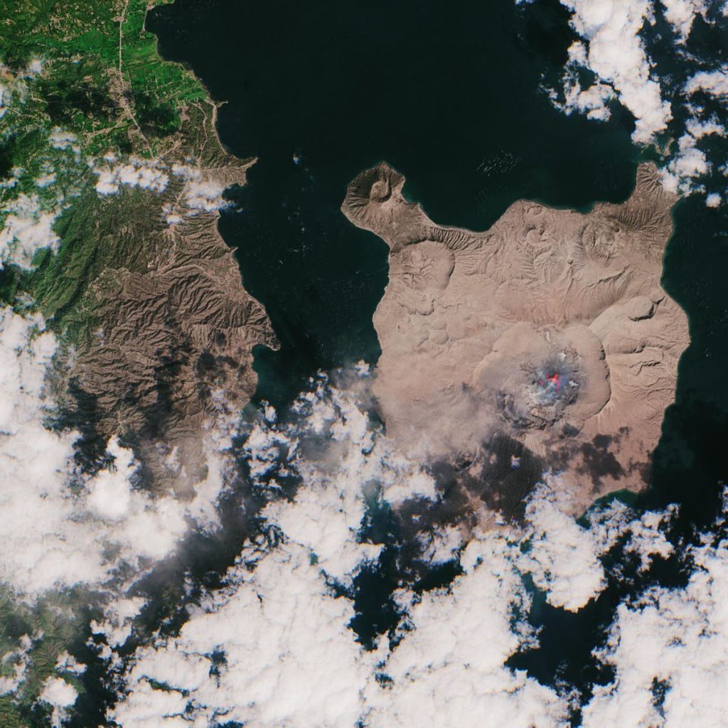 volcano erupting with ash cloud over island coast